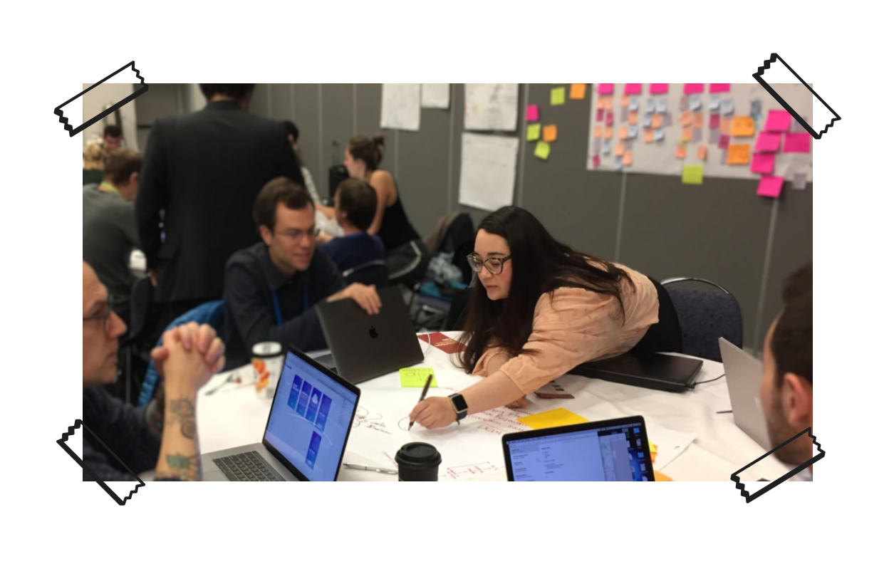 Image of Daniela scribbling on a piece of paper with a marker in a room of other people.